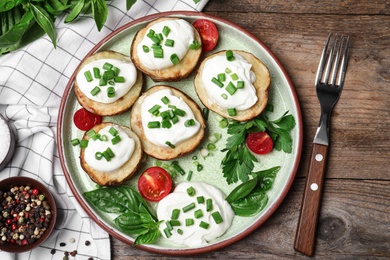 Photo of Delicious potato wedges with sour cream served on wooden table, flat lay