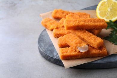 Fresh breaded fish fingers served on grey table, space for text