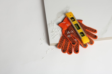 Composition with ceramic tiles and gloves on white background, top view