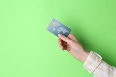 Photo of Woman holding credit card on light green background, closeup