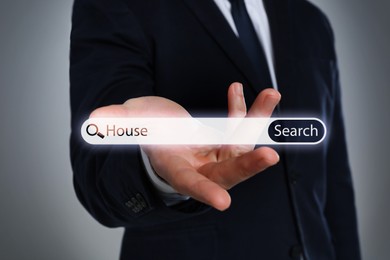 Image of Real estate agent holding virtual search bar with word House on grey background, closeup