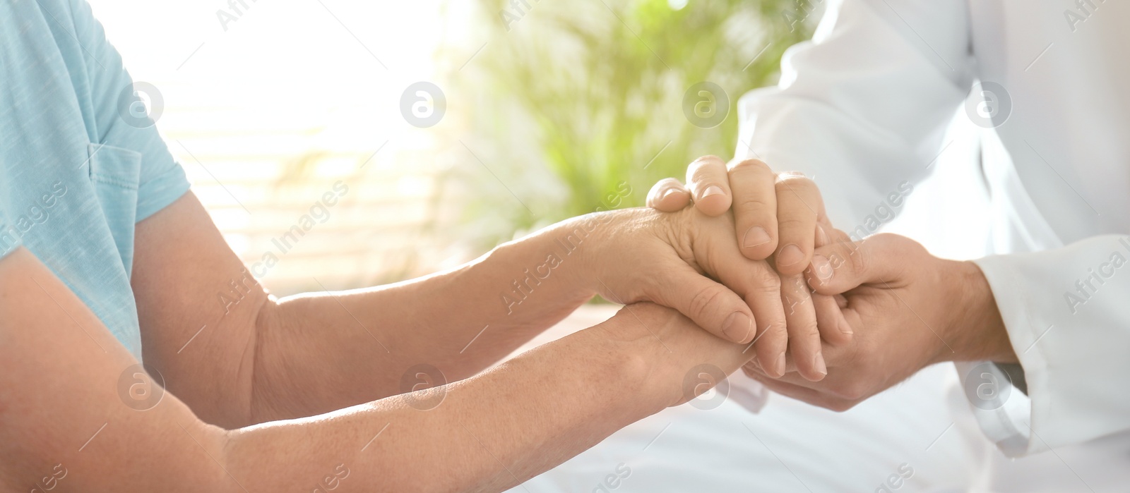 Image of Doctor and senior patient holding hands in hospital, closeup. Banner design