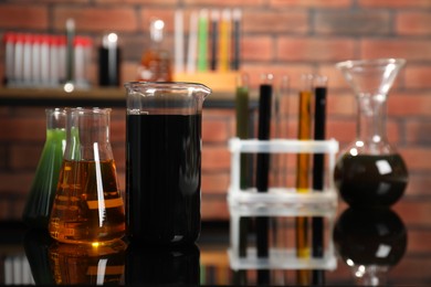 Laboratory glassware with different types of oil on mirror table indoors, closeup