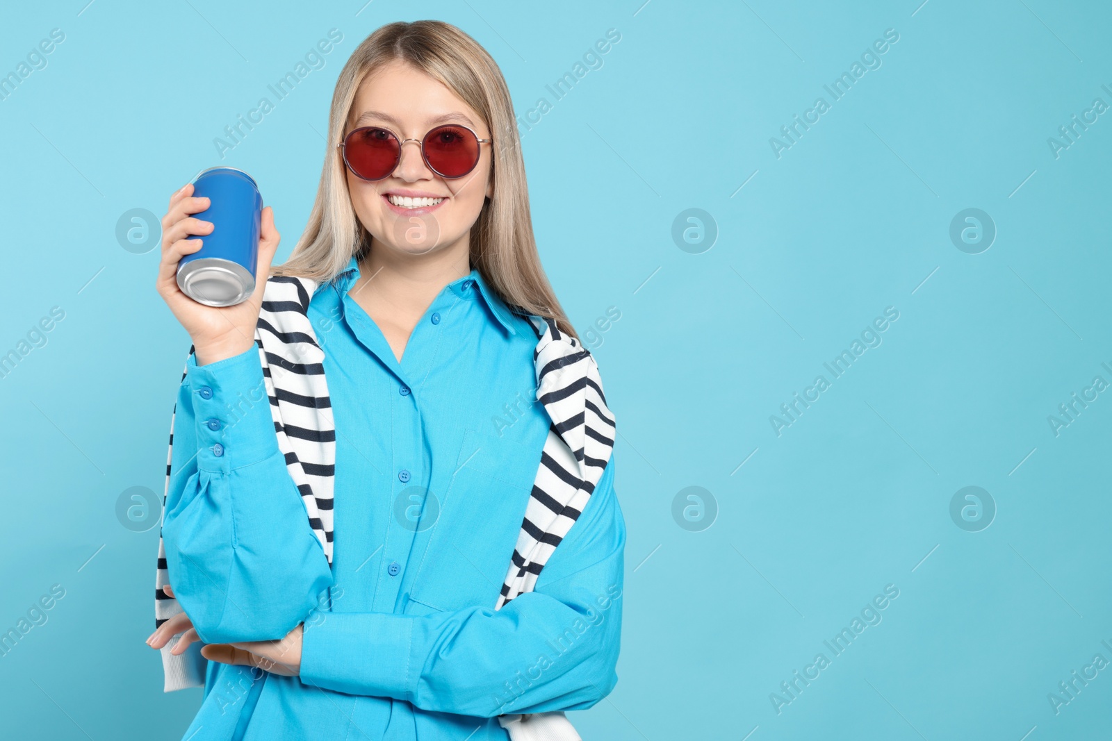 Photo of Beautiful happy woman holding beverage can on light blue background. Space for text