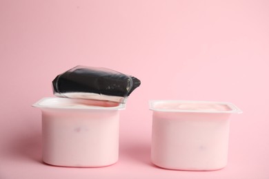 Photo of Tasty organic yogurt in plastic cups on pink background