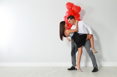 Photo of Beautiful couple with heart shaped balloons dancing on light background, space for text