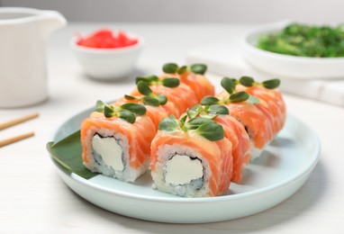 Tasty sushi rolls with salmon served on white table