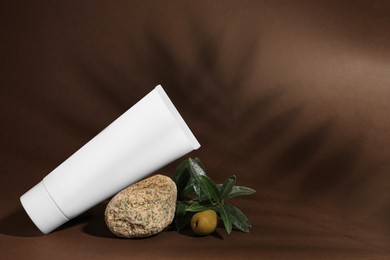 Tube of natural cream, stone and olive on brown background, space for text. Cosmetic products