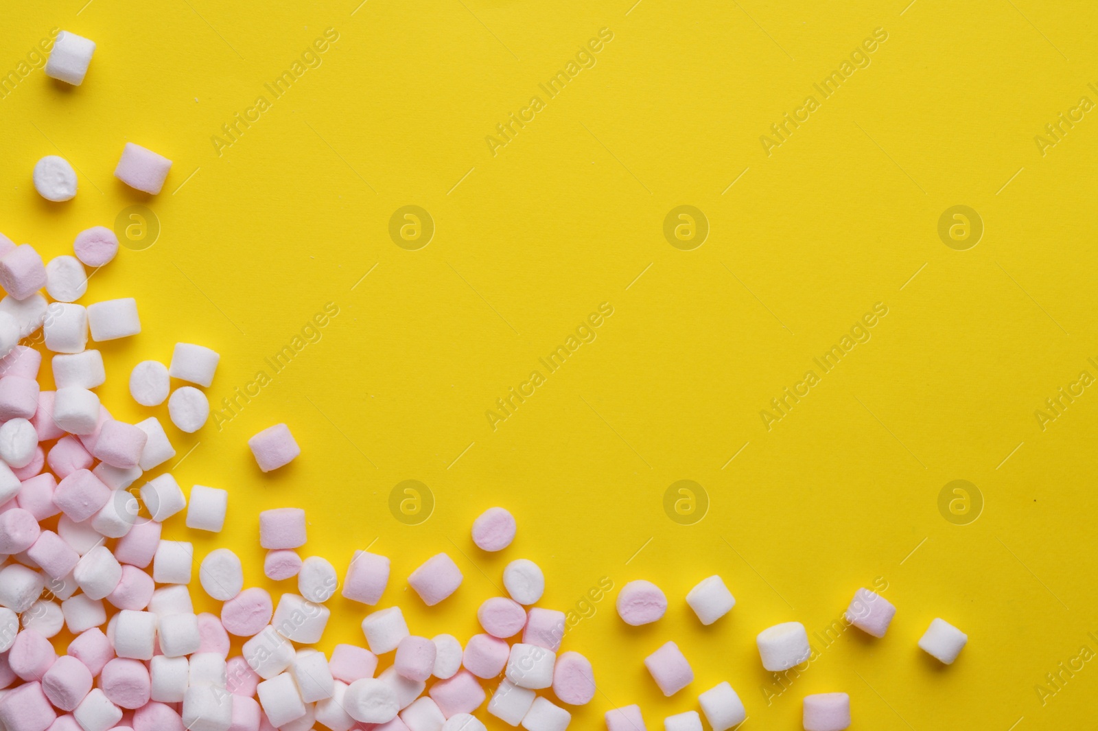 Photo of Delicious marshmallows on yellow background, flat lay. Space for text