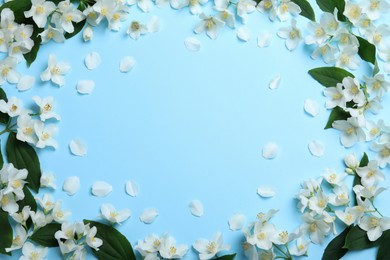 Photo of Frame of beautiful jasmine flowers on light blue background, flat lay. Space for text