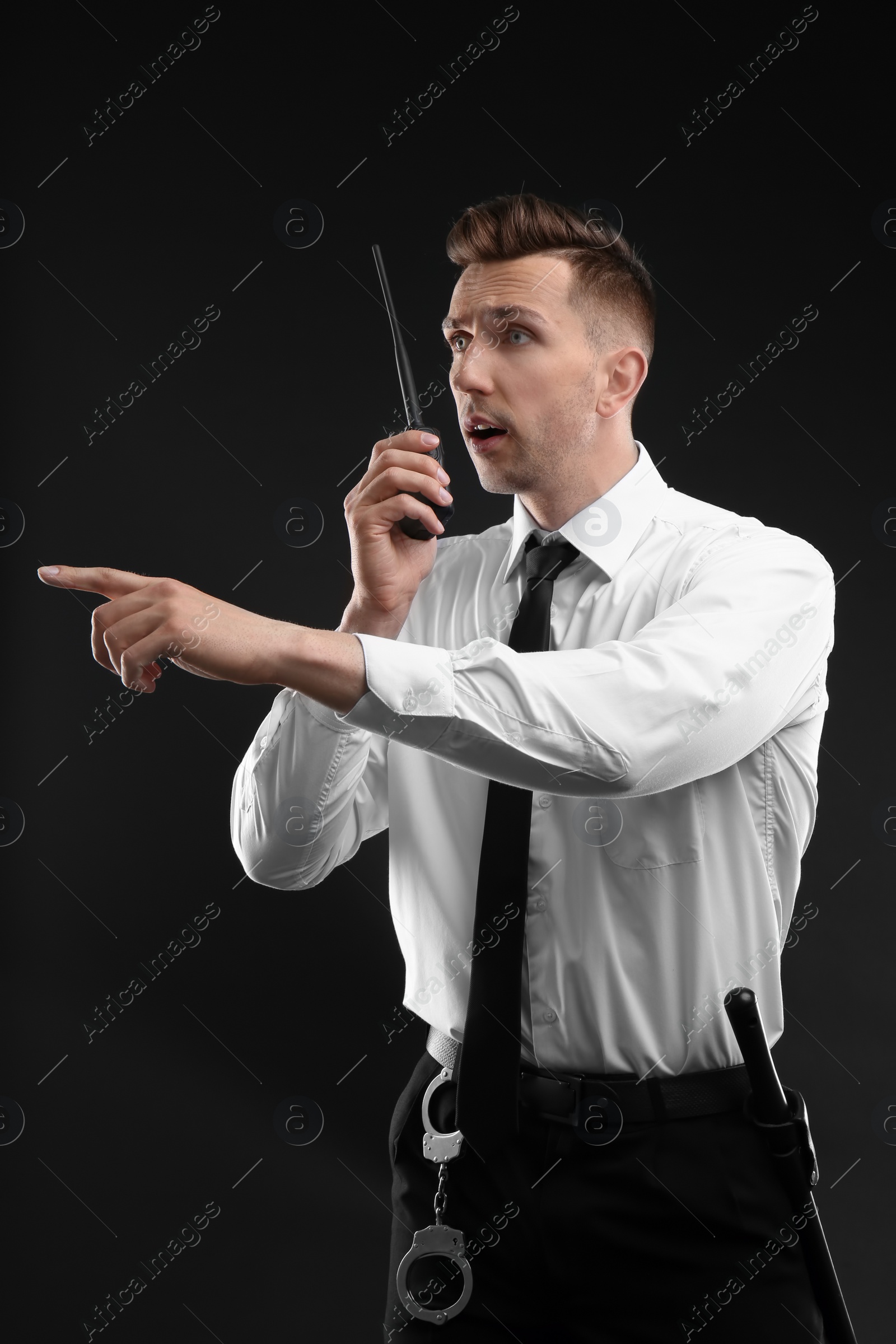 Photo of Male security guard using portable radio transmitter on dark background