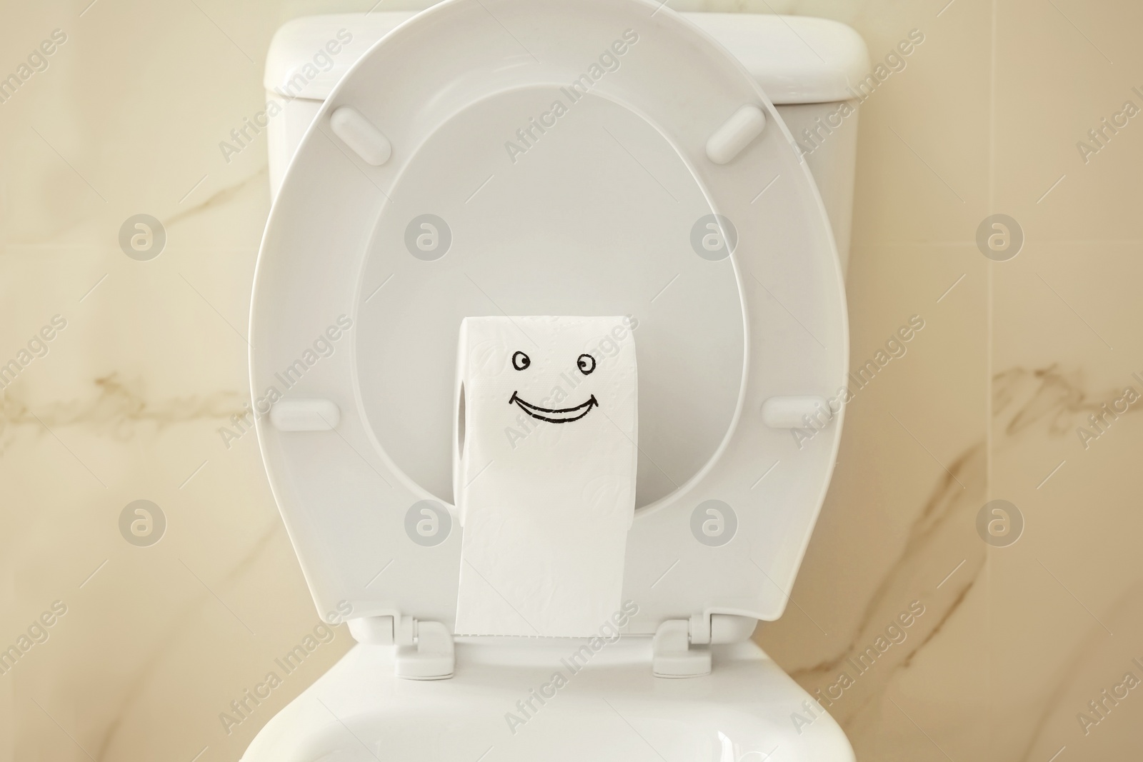 Photo of Roll of paper with funny face on toilet bowl in bathroom