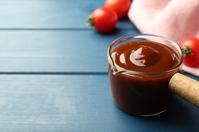 Photo of Tasty barbeque sauce on blue wooden table, closeup. Space for text