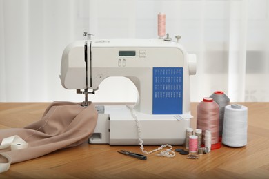 Photo of Sewing machine with fabric and craft accessories on wooden table indoors