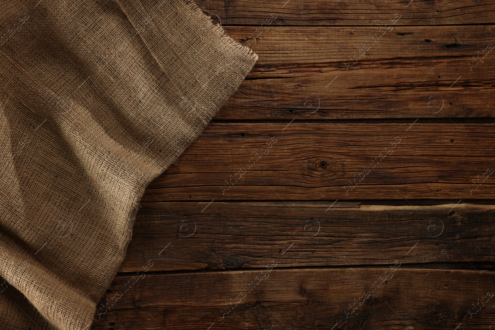 Photo of Burlap fabric on wooden table, top view. Space for text