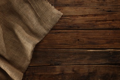 Burlap fabric on wooden table, top view. Space for text