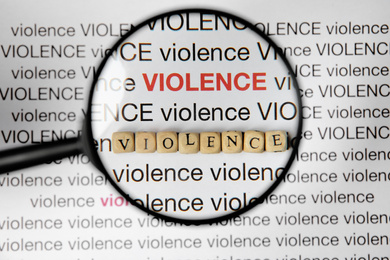 Photo of Word VIOLENCE made of wooden cubes under magnifying glass on white background, top view