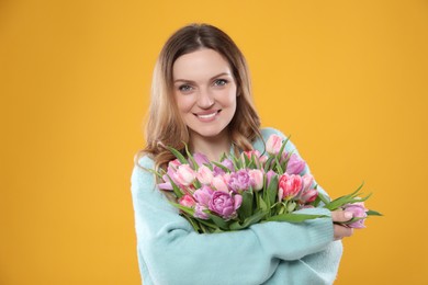 Photo of Happy young woman with bouquet of beautiful tulips on yellow background