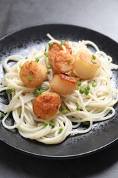 Delicious scallop pasta with green onion on grey table, closeup