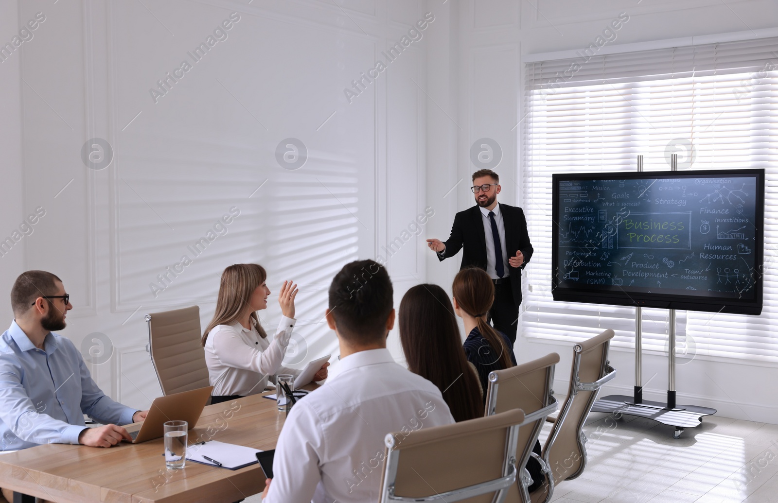 Photo of Business trainer near interactive board in meeting room during presentation