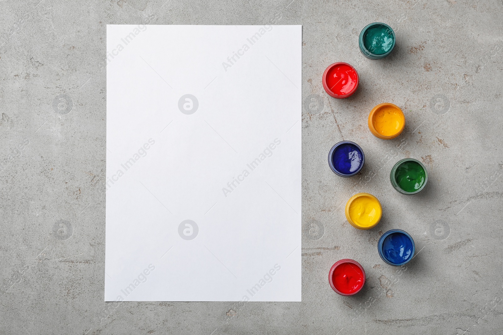 Photo of Flat lay composition with different paints and sheet of paper on grey background. Color palette