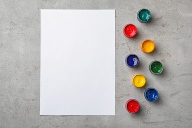 Photo of Flat lay composition with different paints and sheet of paper on grey background. Color palette