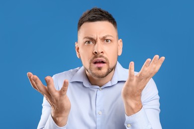 Photo of Emotional man in casual outfit on blue background