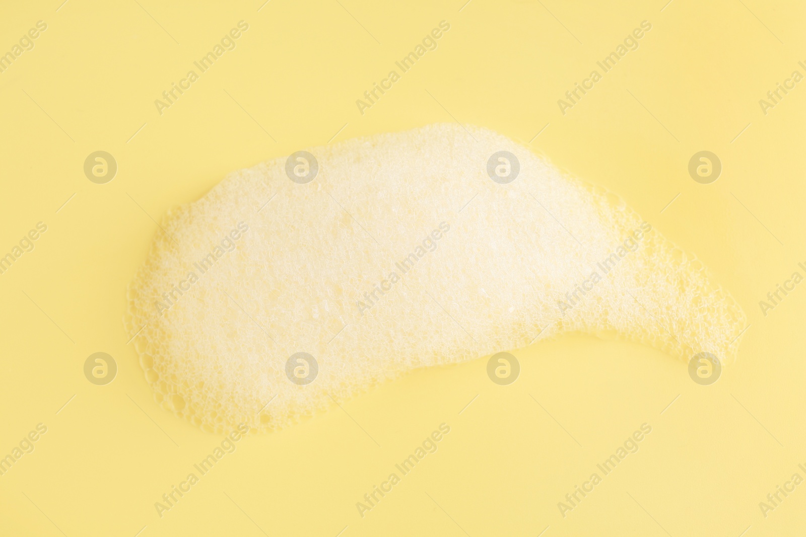 Photo of Sample of fluffy foam on yellow background, top view