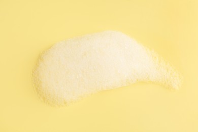 Photo of Sample of fluffy foam on yellow background, top view