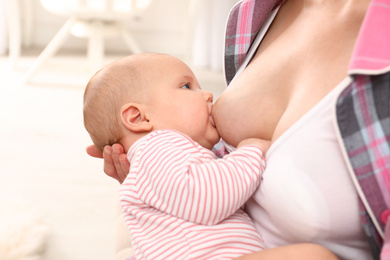 Young woman breastfeeding her little baby at home, closeup