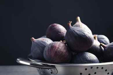 Colander with fresh ripe figs against black background, closeup