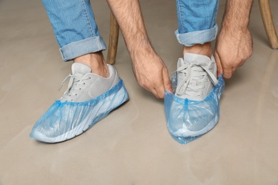 Photo of Man putting on blue shoe covers, closeup