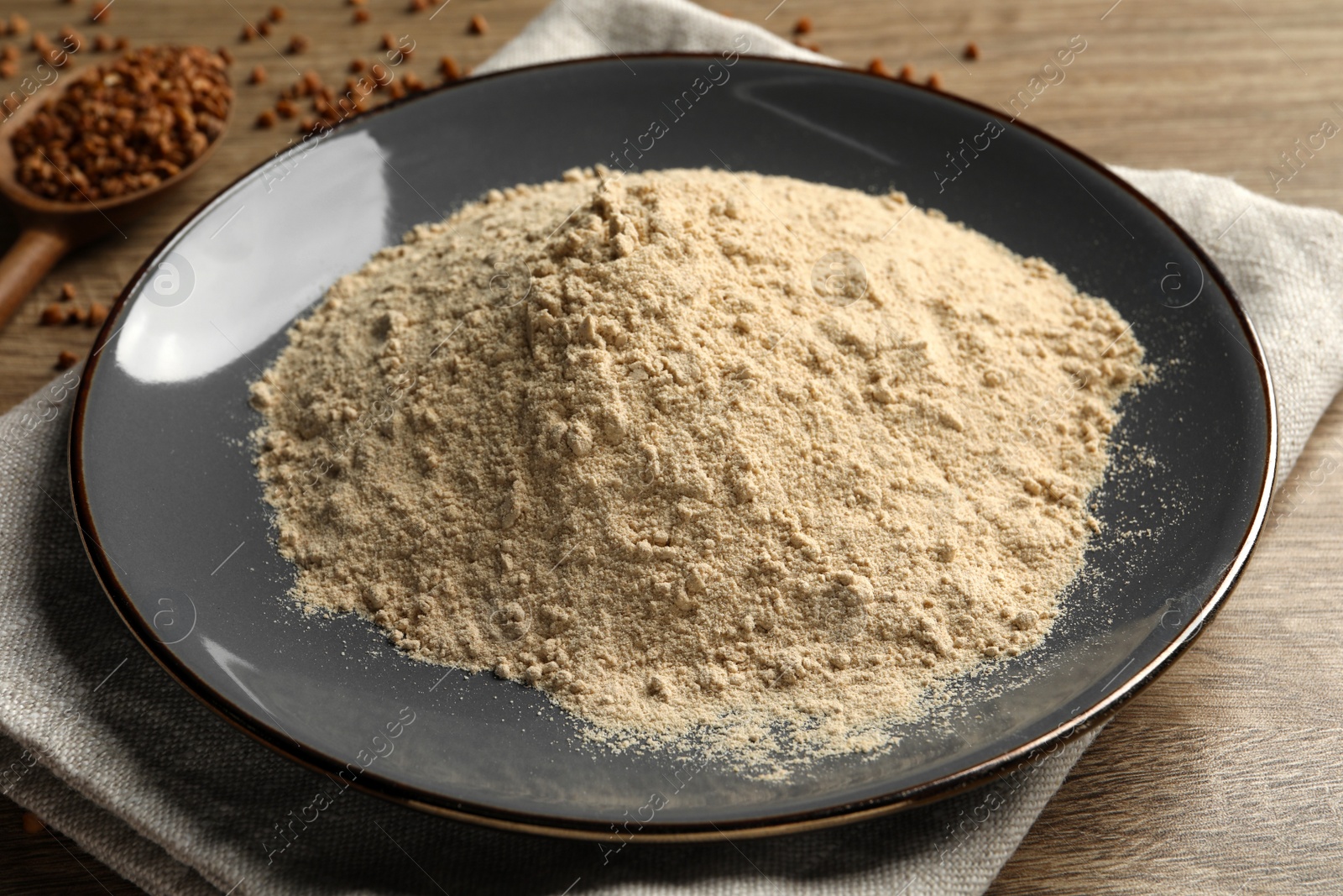 Photo of Plate with buckwheat flour on wooden table, closeup