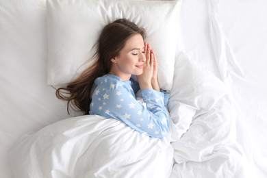 Young woman sleeping on comfortable pillow in bed at home, top view