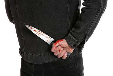 Photo of Man with bloody knife behind his back on white background, closeup. Dangerous criminal