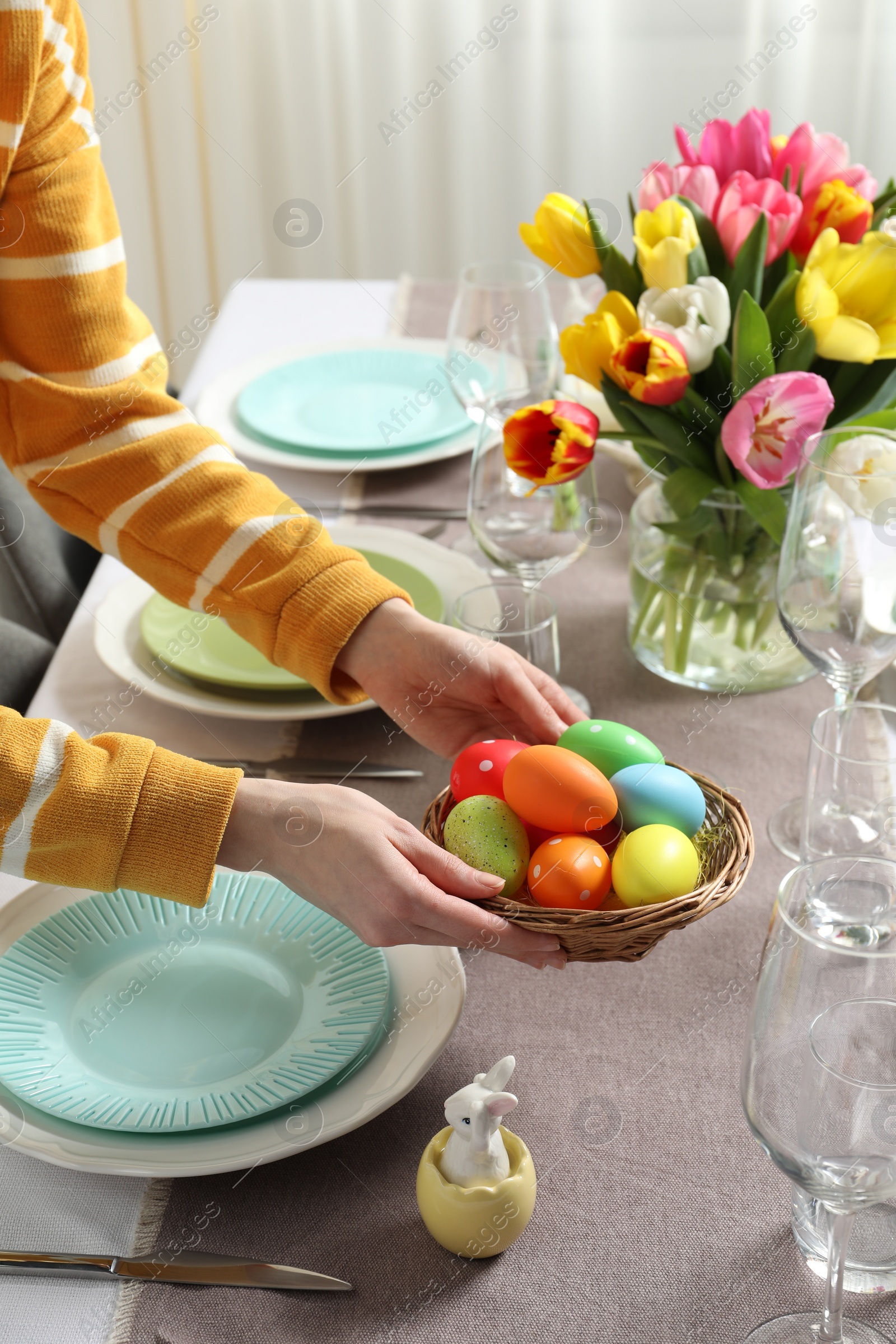 Photo of Woman setting table for festive Easter dinner at home, closeup