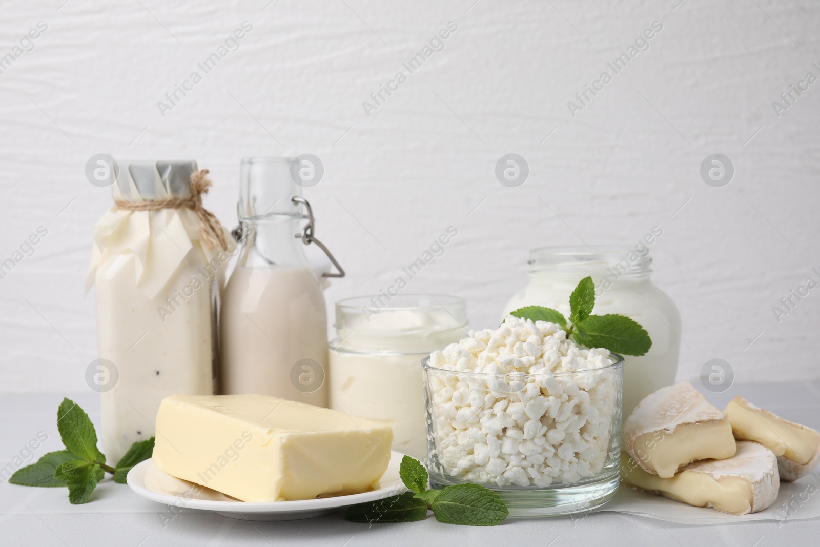 Photo of Different dairy products and mint on white table