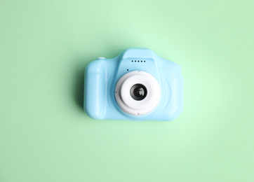 Photo of Light blue toy camera on light green background, top view. Future photographer