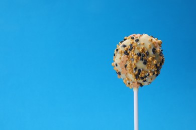 Photo of Delicious confectionery. Sweet cake pop decorated with sprinkles on light blue background, closeup. Space for text