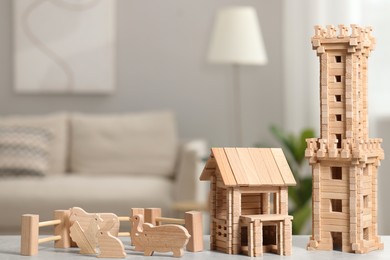 Wooden house, tower and animals on light grey table indoors. Children's toys