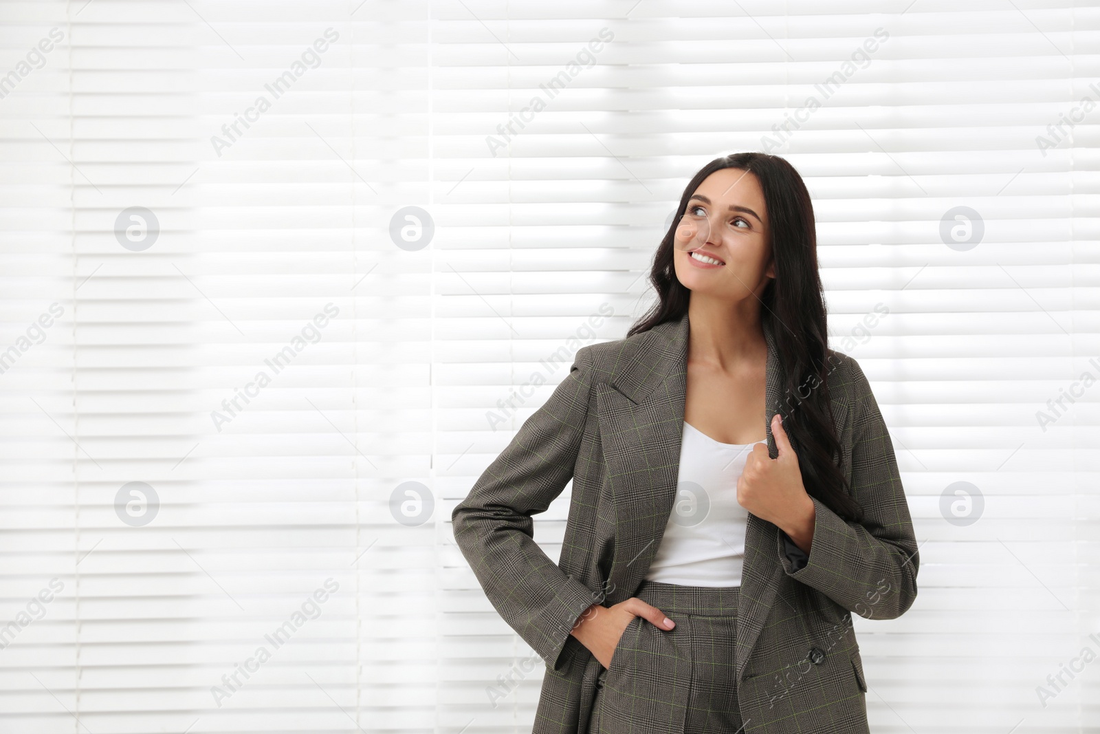 Photo of Beautiful woman in formal suit near window, space for text. Business attire