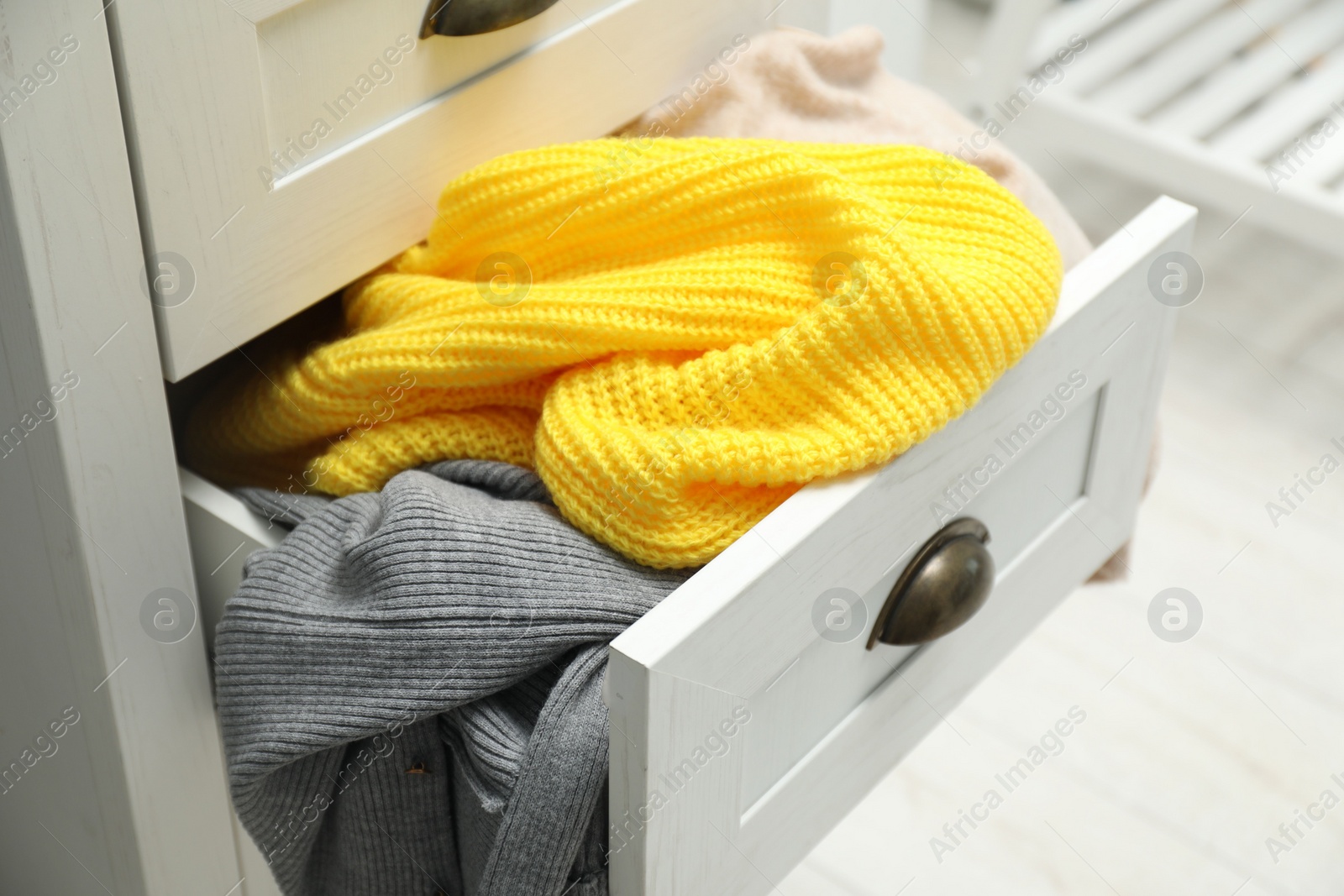 Photo of Cluttered chest of drawers indoors. Clothes in mess