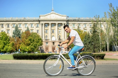 Handsome young hipster man riding bicycle outdoors