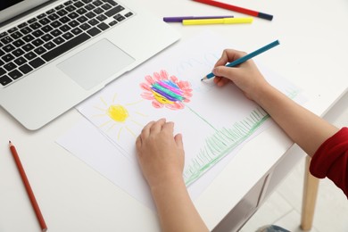 Little girl drawing on paper with pencil at online lesson indoors, closeup. Distance learning