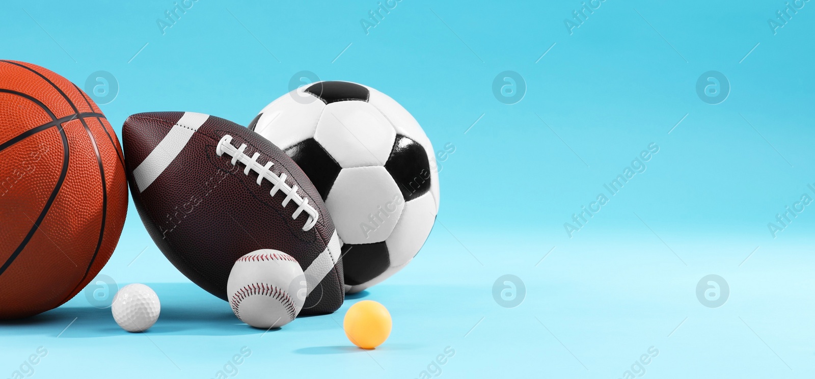 Photo of Many different sports balls on light blue background, space for text. Banner design