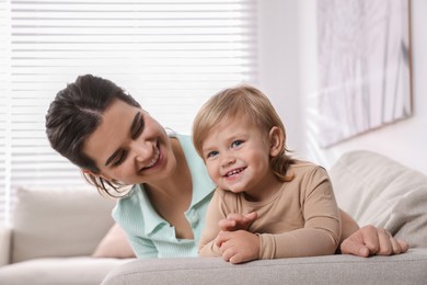 Mother with her cute little daughter on sofa at home