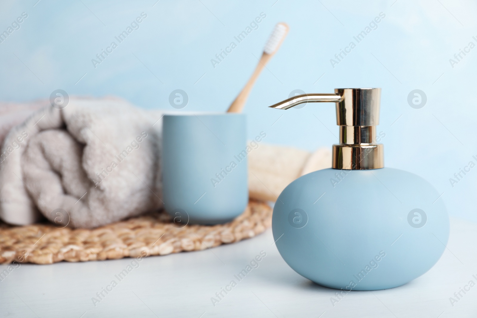 Photo of Stylish soap dispenser, holder with toothbrush and towel on table. Space for text