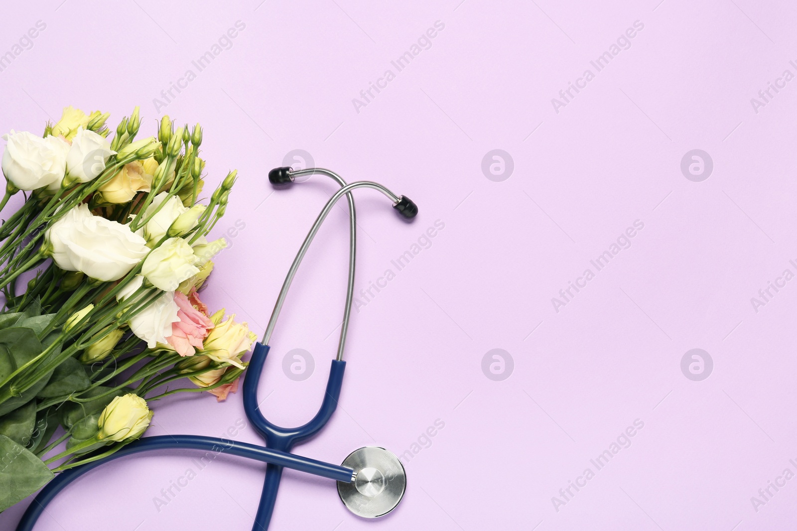 Photo of Stethoscope and beautiful flowers on light violet background, flat lay with space for text. Happy Doctor's Day