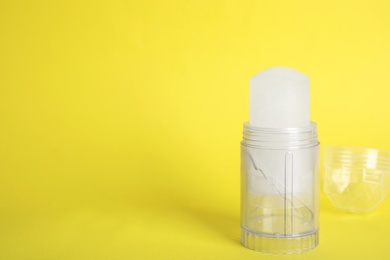 Natural crystal alum stick deodorant and cap on yellow background. Space for text