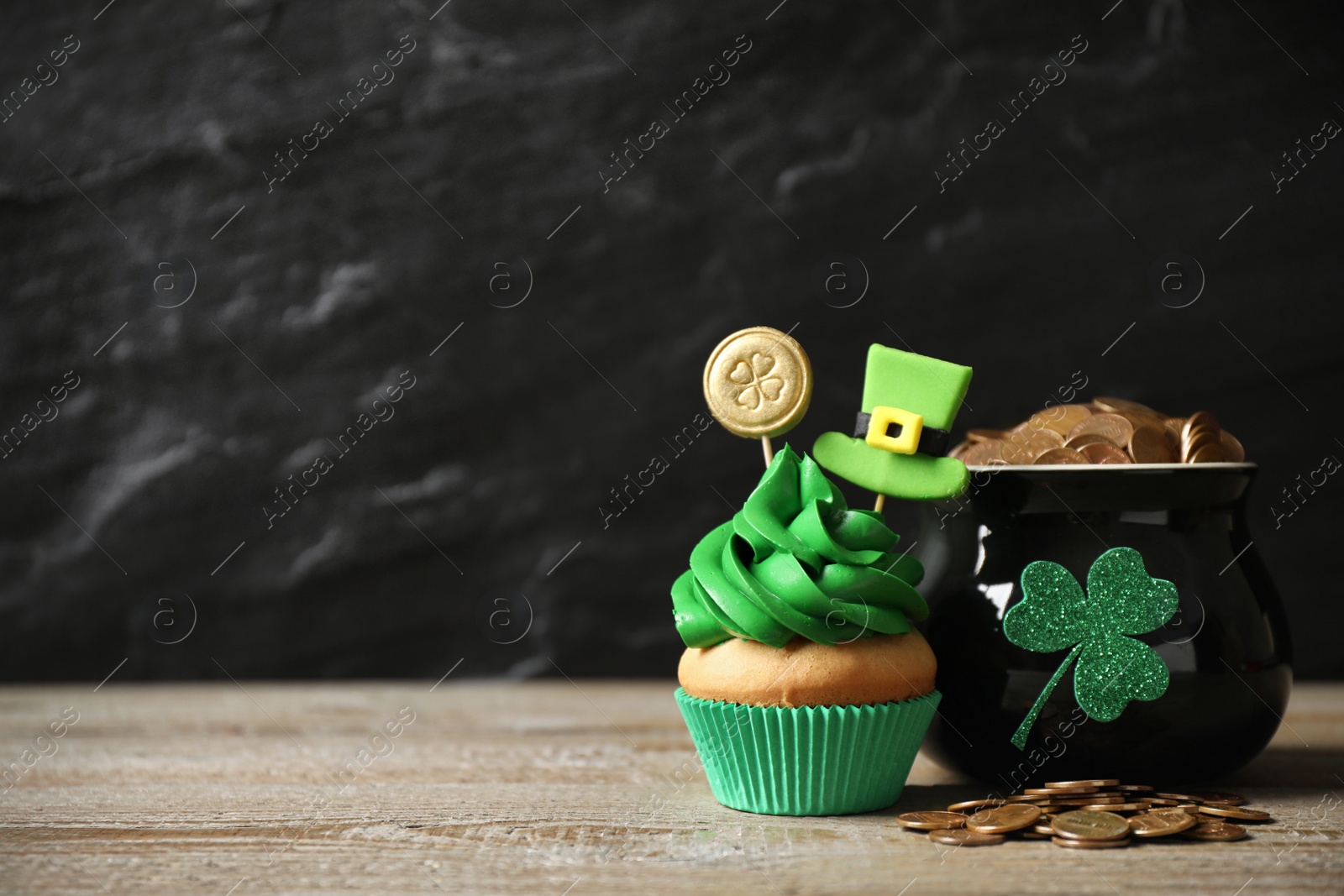 Photo of Decorated cupcake and pot with gold coins on wooden table, space for text. St. Patrick's Day celebration